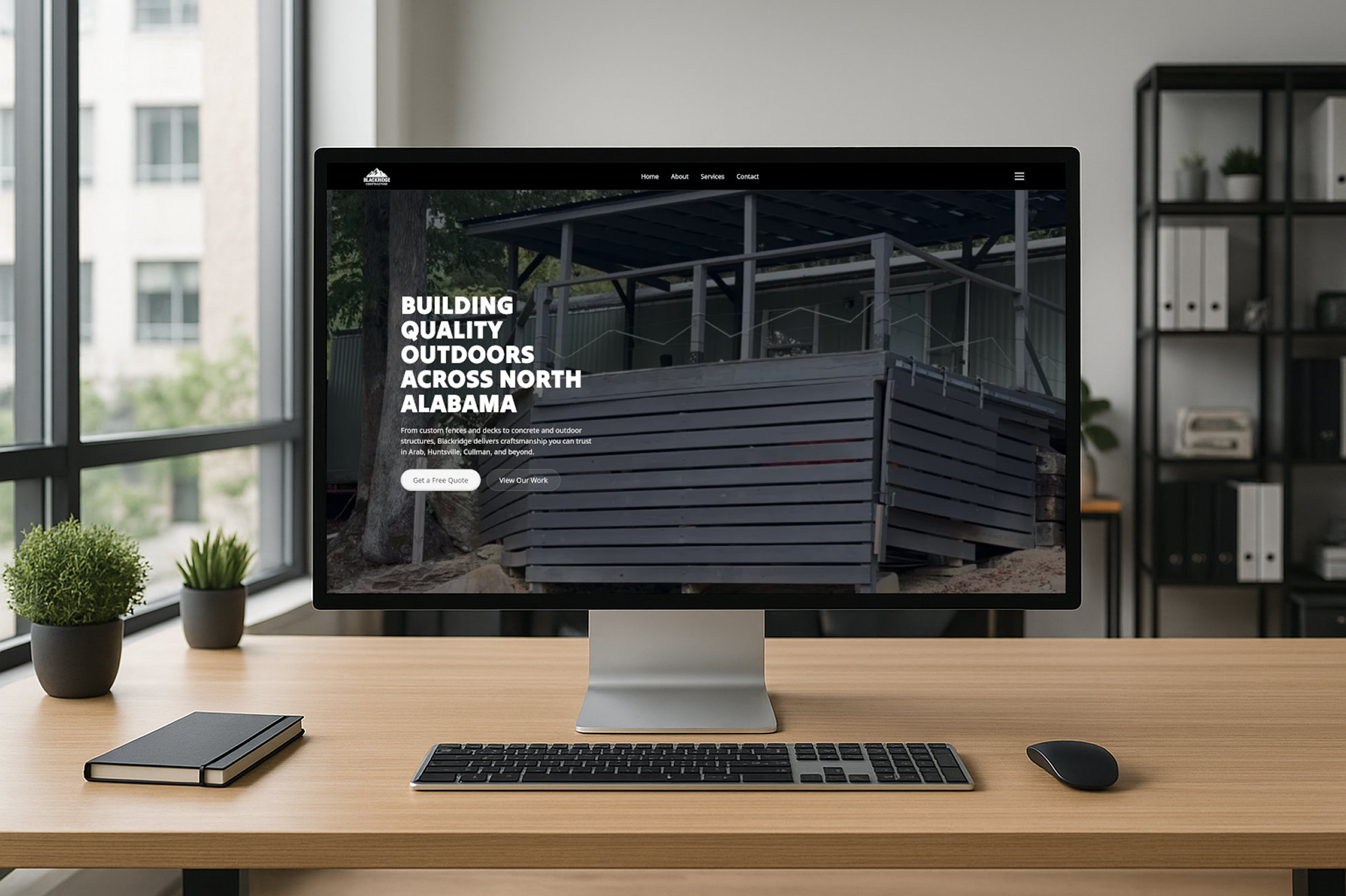 Modern desktop computer on wooden desk displaying a website for outdoor construction services in North Alabama.